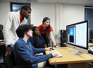 Communication students looking at computer monitor together at internships.