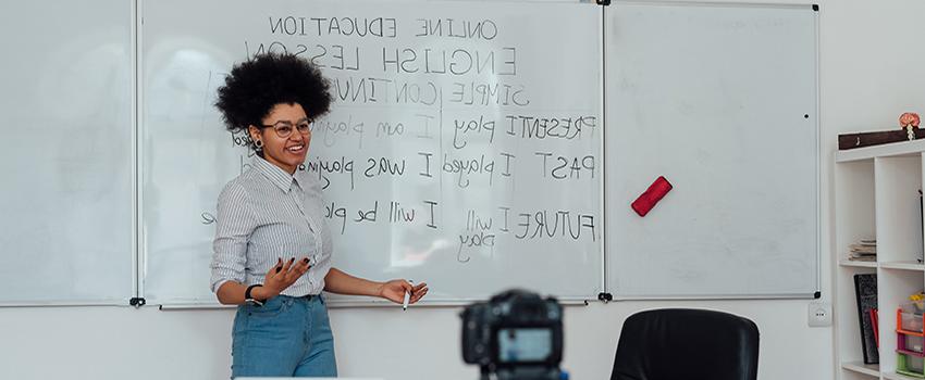 Female teaching English language at white board.