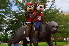 Southpaw and Miss Pawla sitting on the jaguar statue in front of the Mitchell Center. 