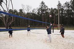 Students playing sand volleyball on campus.