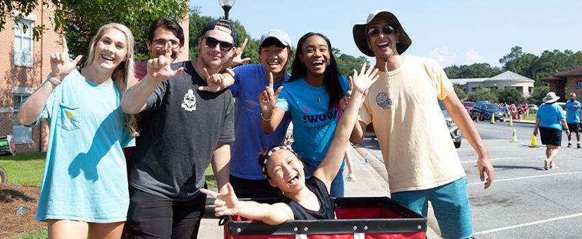 Students at move in day holding up the J sign.