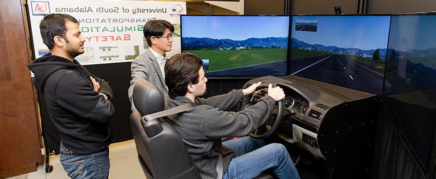 土木工程系学生与教授一起使用驾驶模拟器.